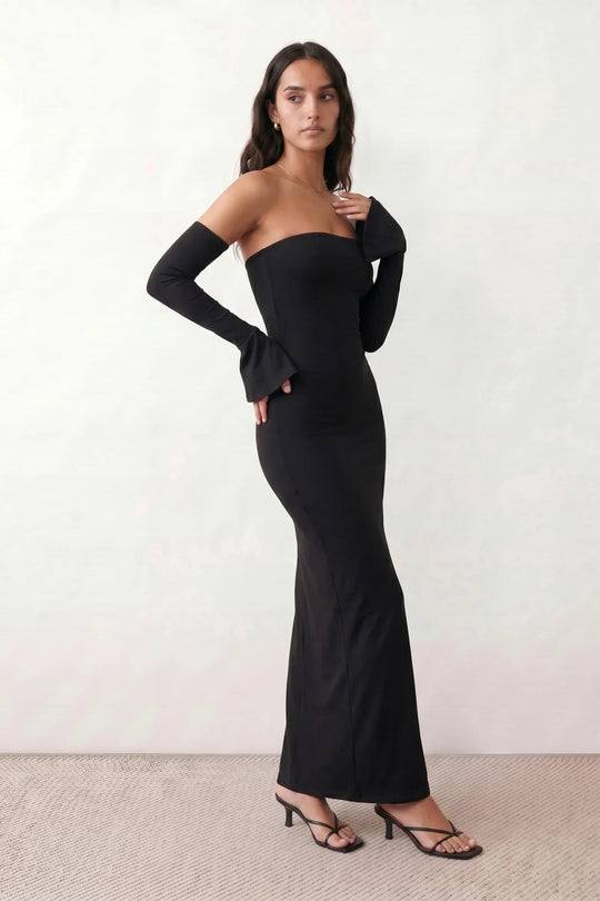 Woman wearing the strapless mermaid maxi dress with a sweetheart neckline, statement shoulder bow, matching long bell-cuff gloves, fitted silhouette and floor-length hem, ideal for weddings, black-tie events and formal occasions.