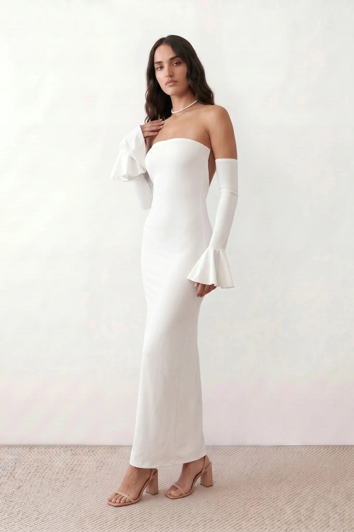 Woman wearing the strapless mermaid maxi dress with a sweetheart neckline, statement shoulder bow, matching long bell-cuff gloves, fitted silhouette and floor-length hem, ideal for weddings, black-tie events and formal occasions.