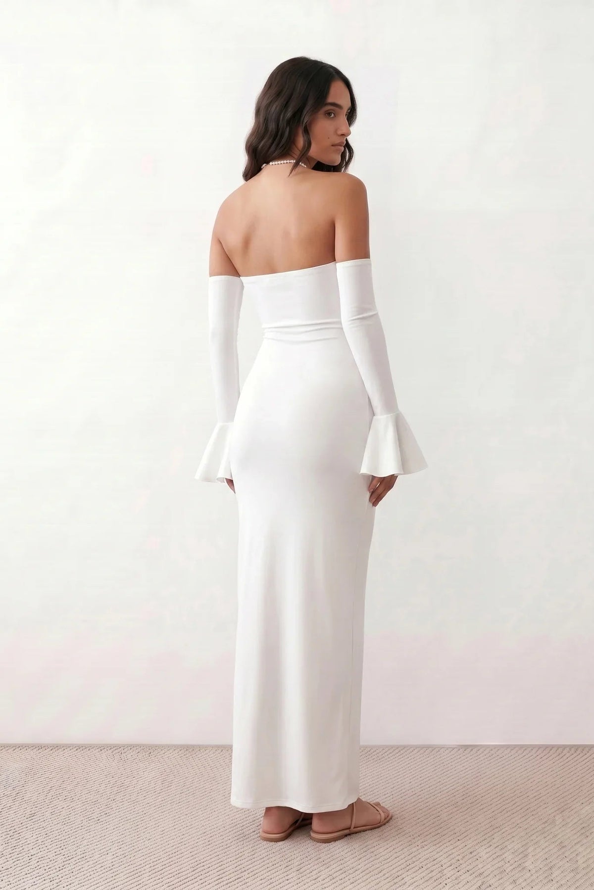 Woman wearing the strapless mermaid maxi dress with a sweetheart neckline, statement shoulder bow, matching long bell-cuff gloves, fitted silhouette and floor-length hem, ideal for weddings, black-tie events and formal occasions.