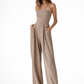 Woman wearing a beige strapless jumpsuit on a white background