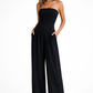 Woman wearing a black strapless jumpsuit on a white background
