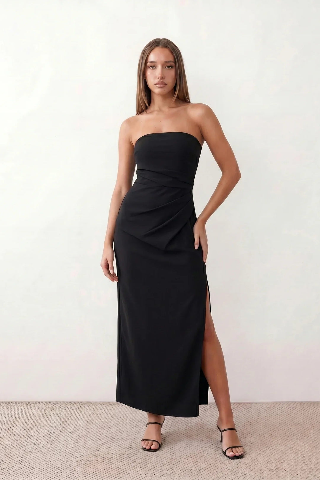 Woman wearing the strapless square neck fitted maxi dress with a structured fold-over bodice, ruched waist, low back and side slit, elegant full-length evening gown for weddings, black-tie events and formal occasions.