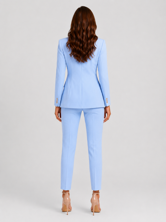 Woman wearing a tailored double-breasted blazer and matching trousers set with a structured silhouette and polished modern tailoring.