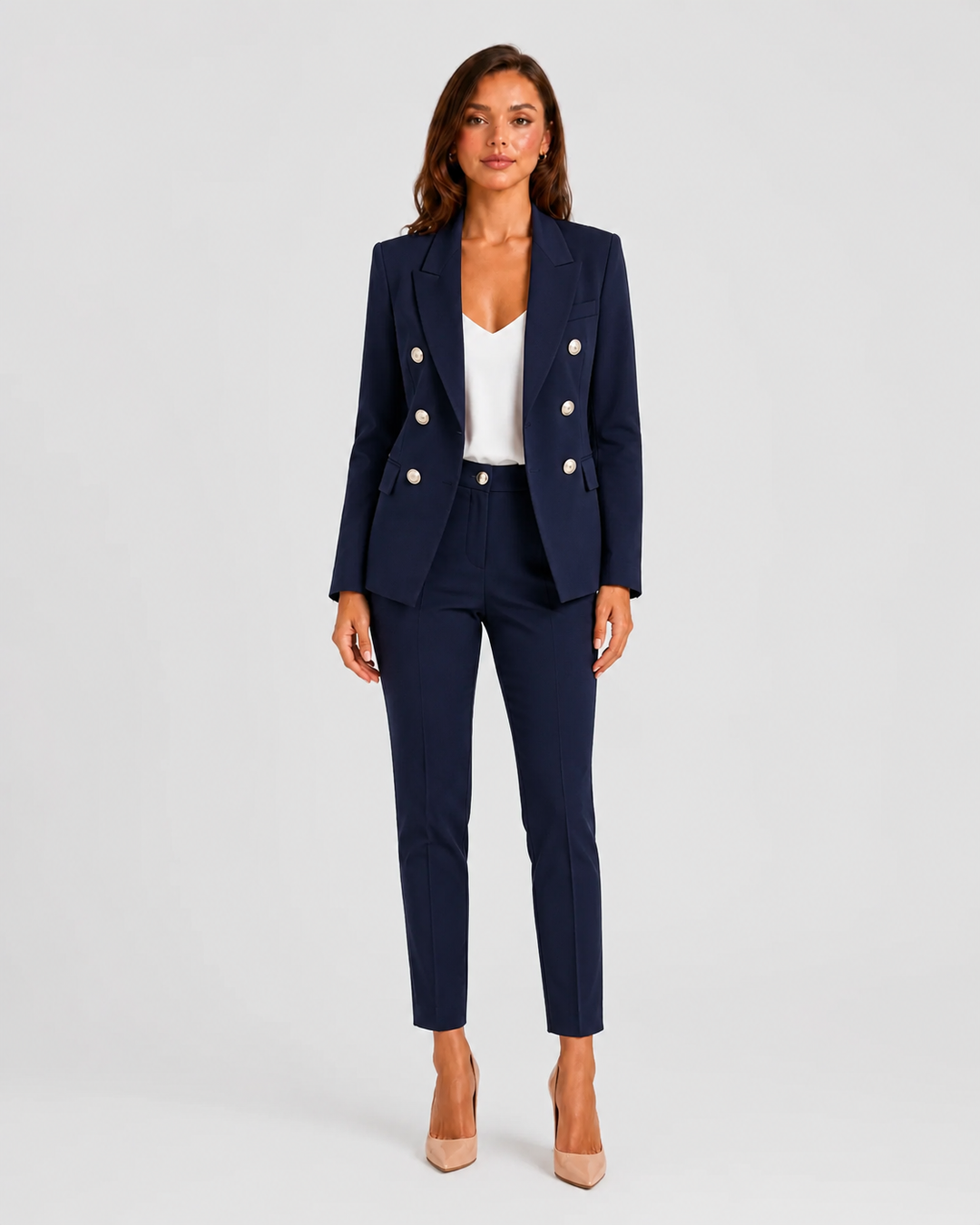 Woman wearing a tailored double-breasted blazer and matching trousers set with a structured silhouette and polished modern tailoring.