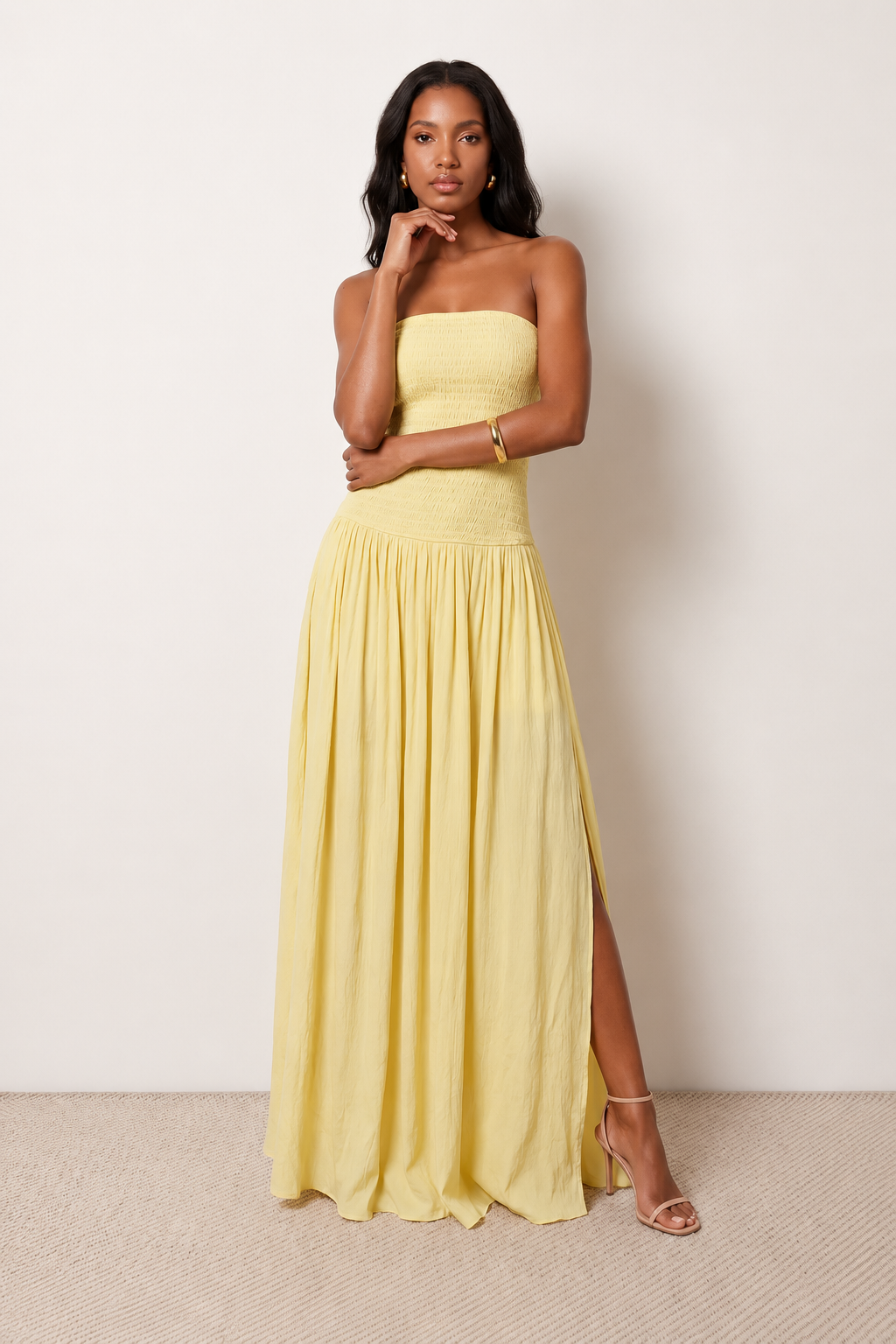Woman wearing the Zofia strapless A-line maxi dress featuring a smocked square-neck bodice, shirred waist, flowing A-line skirt with a side slit, and a backless design.