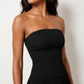 Woman wearing the Zofia strapless A-line maxi dress featuring a smocked square-neck bodice, shirred waist, flowing A-line skirt with a side slit, and a backless design.