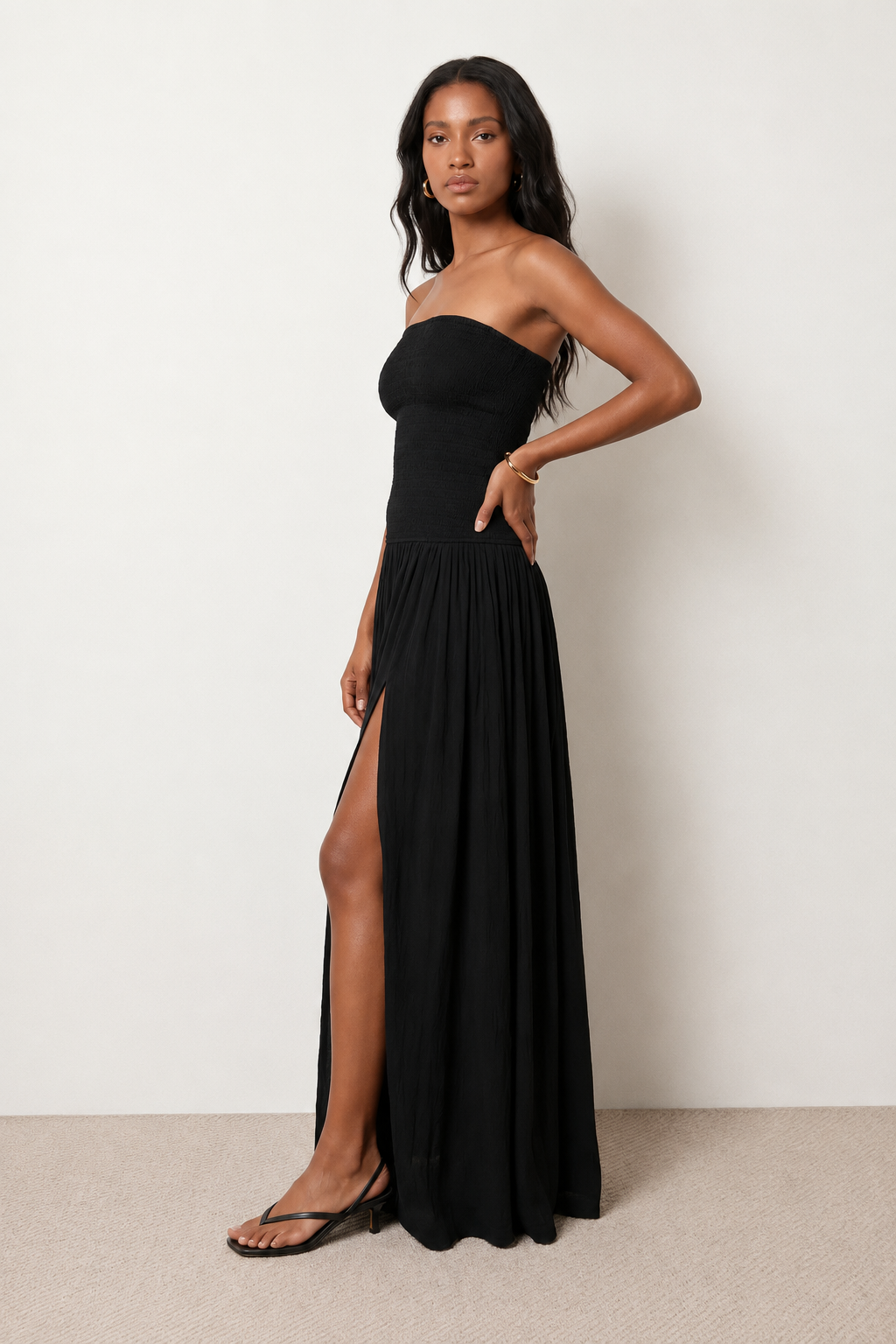 Woman wearing the Zofia strapless A-line maxi dress featuring a smocked square-neck bodice, shirred waist, flowing A-line skirt with a side slit, and a backless design.
