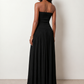 Woman wearing the Zofia strapless A-line maxi dress featuring a smocked square-neck bodice, shirred waist, flowing A-line skirt with a side slit, and a backless design.