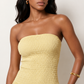 Woman wearing the Zofia strapless A-line maxi dress featuring a smocked square-neck bodice, shirred waist, flowing A-line skirt with a side slit, and a backless design.