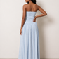 Woman wearing the Zofia strapless A-line maxi dress featuring a smocked square-neck bodice, shirred waist, flowing A-line skirt with a side slit, and a backless design.
