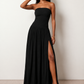 Woman wearing the Zofia strapless A-line maxi dress featuring a smocked square-neck bodice, shirred waist, flowing A-line skirt with a side slit, and a backless design.