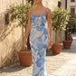 Seren spaghetti strap maxi dress in an abstract floral print featuring a square neckline, thin straps, a low lace-up open back, a shirred waist, and a fitted floor-length silhouette.