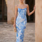 Seren spaghetti strap maxi dress in an abstract floral print featuring a square neckline, thin straps, a low lace-up open back, a shirred waist, and a fitted floor-length silhouette.