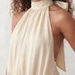 Bella Glossy Halter Mini Dress with a halter mock neckline, tie-back closure, smocked waist, open back, and tiered ruffle mini skirt in a glossy finish, available in Beige, Red, Purple, Yellow, Pink, and Light Blue.