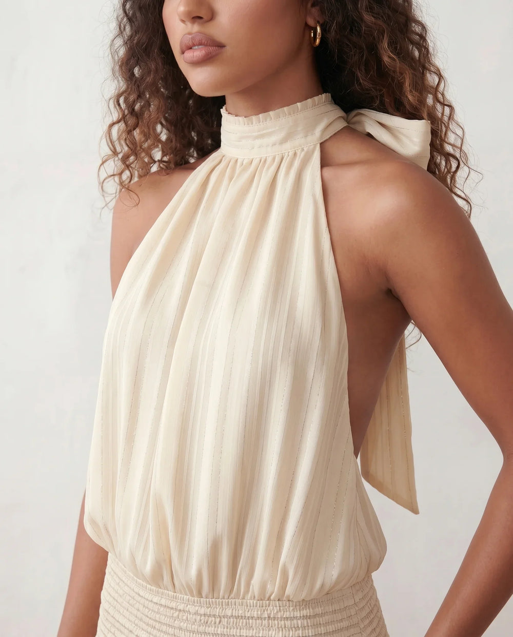 Bella Glossy Halter Mini Dress with a halter mock neckline, tie-back closure, smocked waist, open back, and tiered ruffle mini skirt in a glossy finish, available in Beige, Red, Purple, Yellow, Pink, and Light Blue.
