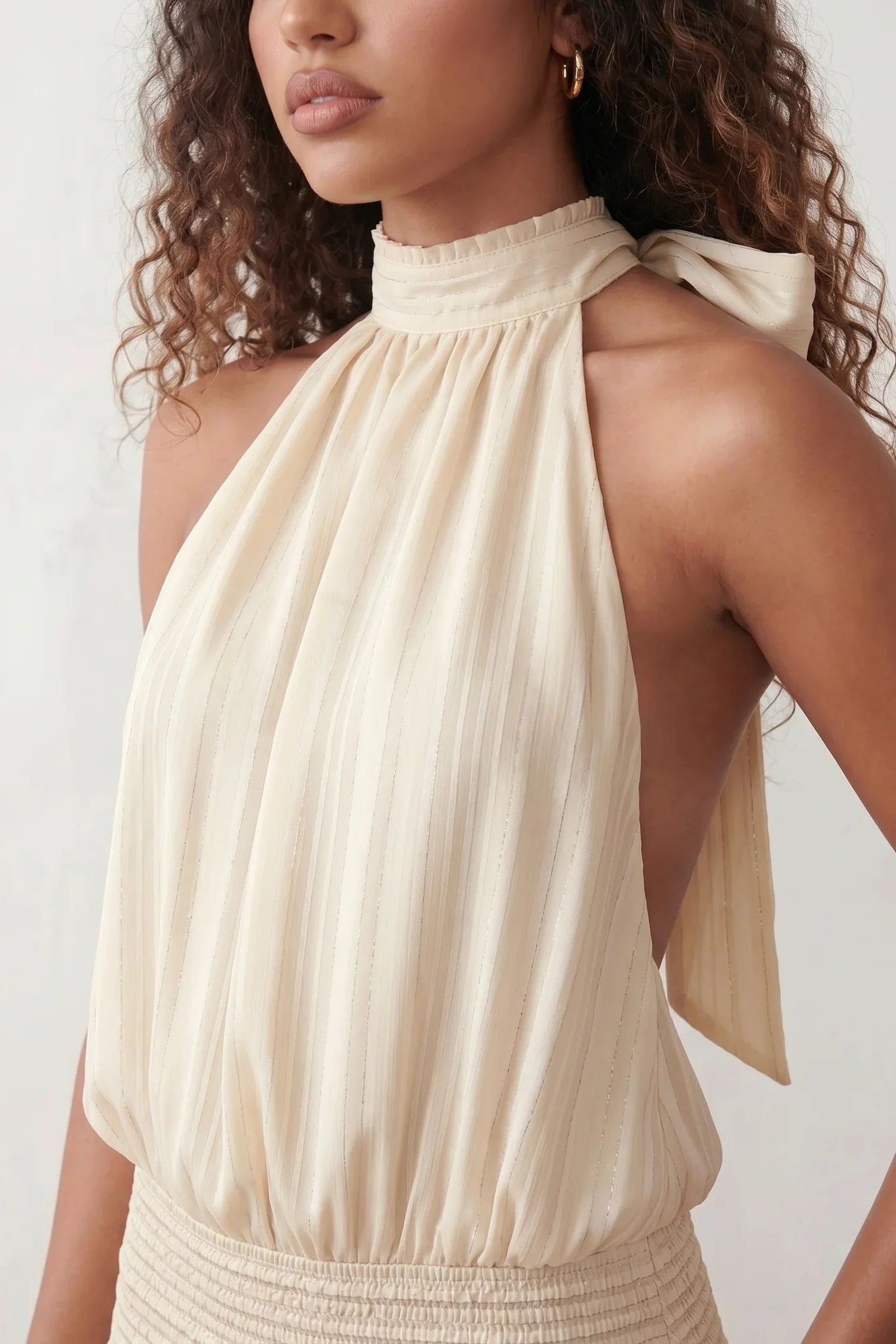 Bella Glossy Halter Mini Dress with a halter mock neckline, tie-back closure, smocked waist, open back, and tiered ruffle mini skirt in a glossy finish, available in Beige, Red, Purple, Yellow, Pink, and Light Blue.