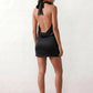 Woman wearing the Mae silk halter mini dress featuring a draped halter neckline, open back with adjustable tie-neck fastening, fitted bodycon mini silhouette, and smooth silk-look fabric, ideal for weddings, cocktail parties, and evening occasions.