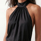 Woman wearing the Mae silk halter mini dress featuring a draped halter neckline, open back with adjustable tie-neck fastening, fitted bodycon mini silhouette, and smooth silk-look fabric, ideal for weddings, cocktail parties, and evening occasions.