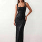Woman wearing the Mihaela sequined low back maxi dress featuring allover sequin mesh, a square neckline, wide shoulder straps, a low open back, and a fitted floor-length sheath silhouette.
