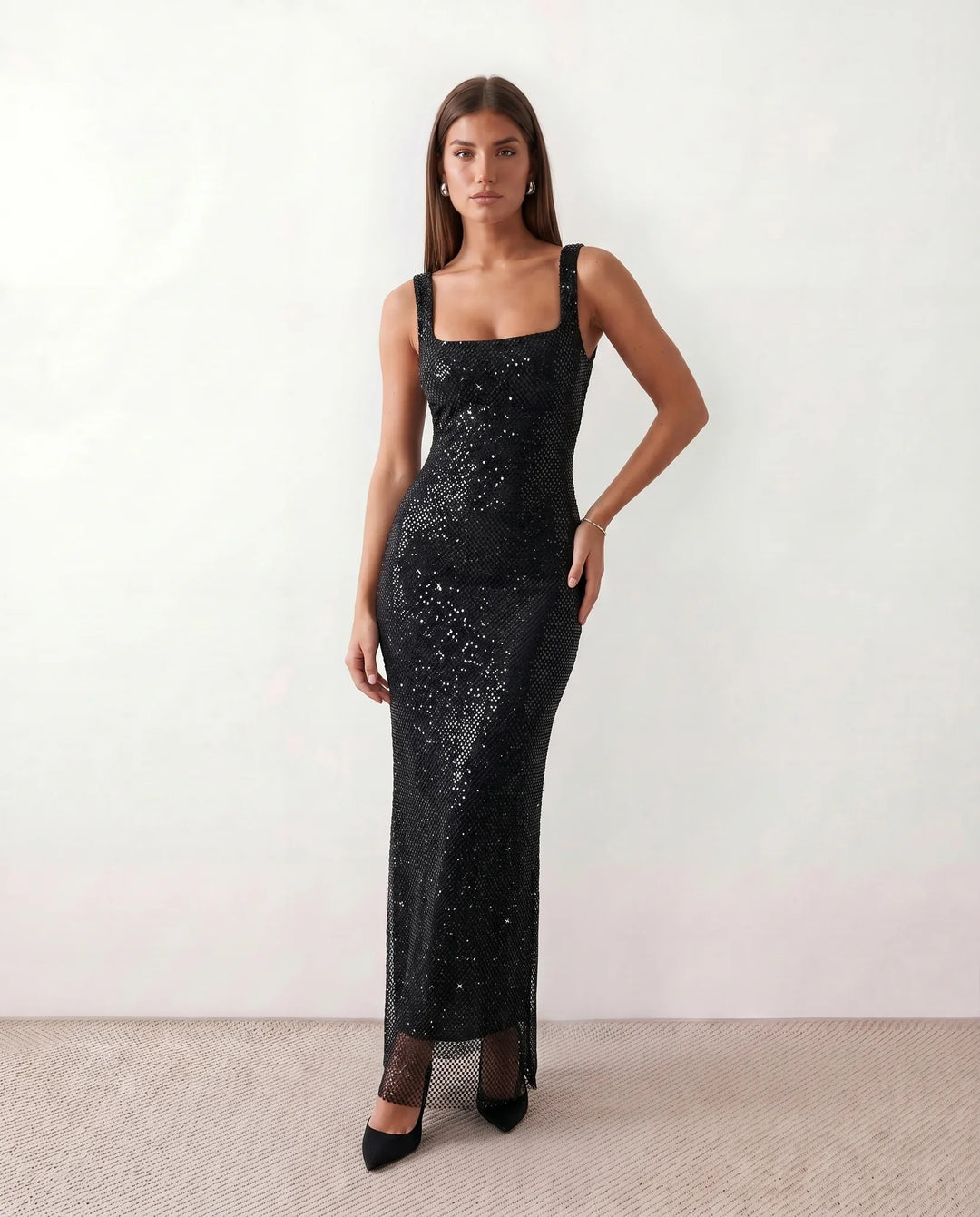 Woman wearing the Mihaela sequined low back maxi dress featuring allover sequin mesh, a square neckline, wide shoulder straps, a low open back, and a fitted floor-length sheath silhouette.
