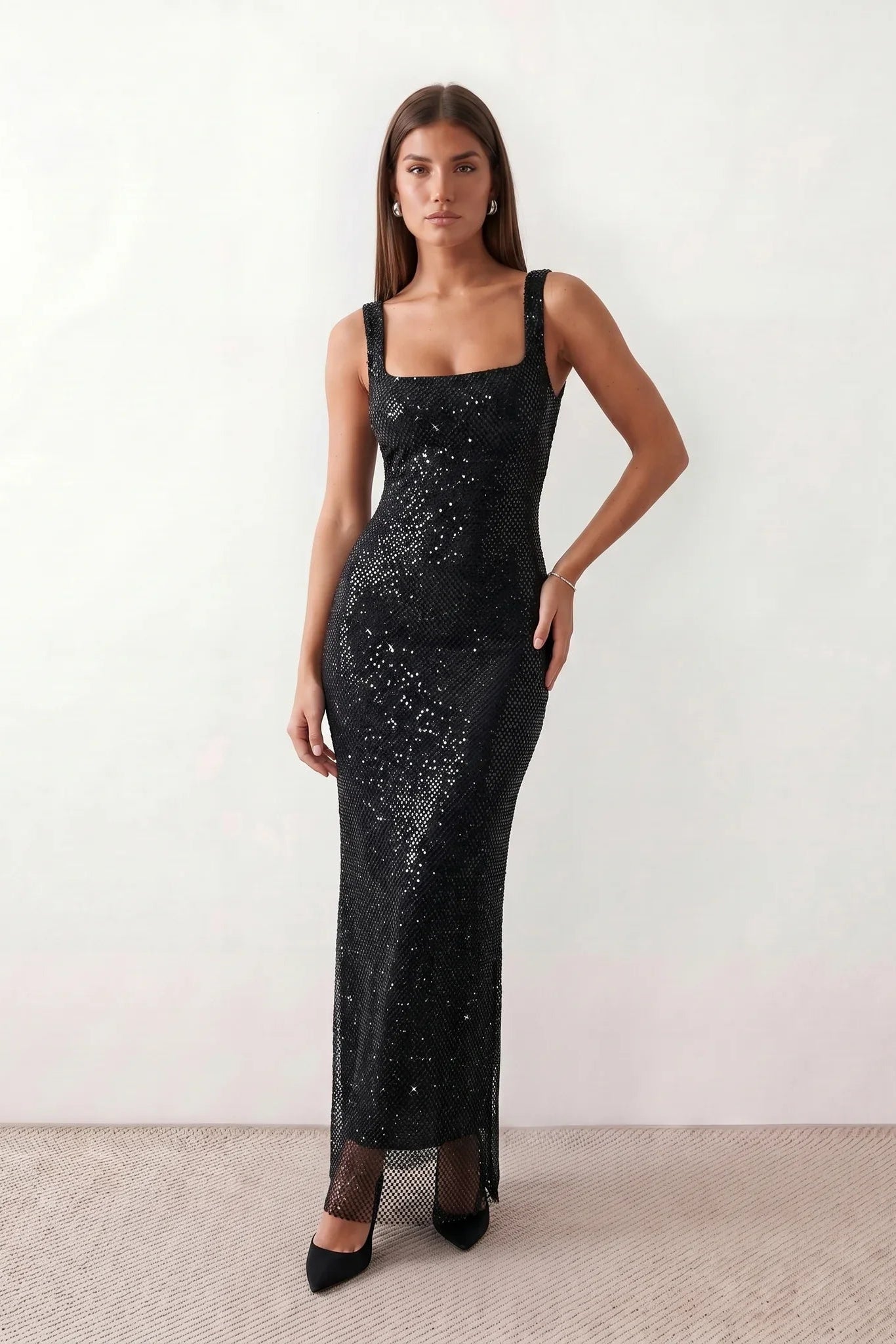 Woman wearing the Mihaela sequined low back maxi dress featuring allover sequin mesh, a square neckline, wide shoulder straps, a low open back, and a fitted floor-length sheath silhouette.