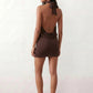 Woman wearing the Mae silk halter mini dress featuring a draped halter neckline, open back with adjustable tie-neck fastening, fitted bodycon mini silhouette, and smooth silk-look fabric, ideal for weddings, cocktail parties, and evening occasions.