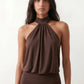 Woman wearing the Mae silk halter mini dress featuring a draped halter neckline, open back with adjustable tie-neck fastening, fitted bodycon mini silhouette, and smooth silk-look fabric, ideal for weddings, cocktail parties, and evening occasions.