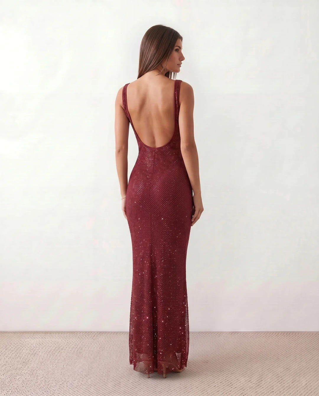 Woman wearing the Mihaela sequined low back maxi dress featuring allover sequin mesh, a square neckline, wide shoulder straps, a low open back, and a fitted floor-length sheath silhouette.