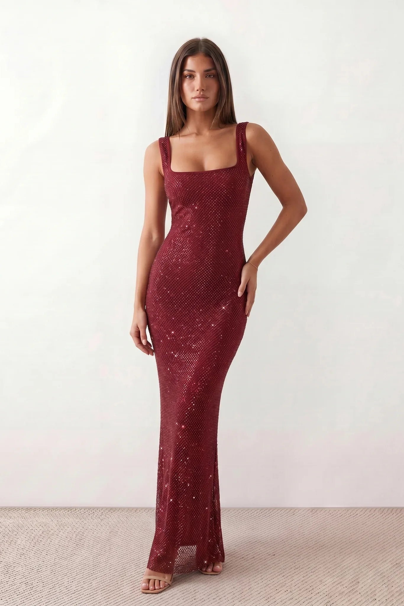 Woman wearing the Mihaela sequined low back maxi dress featuring allover sequin mesh, a square neckline, wide shoulder straps, a low open back, and a fitted floor-length sheath silhouette.