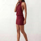 Woman wearing the Mae silk halter mini dress featuring a draped halter neckline, open back with adjustable tie-neck fastening, fitted bodycon mini silhouette, and smooth silk-look fabric, ideal for weddings, cocktail parties, and evening occasions.