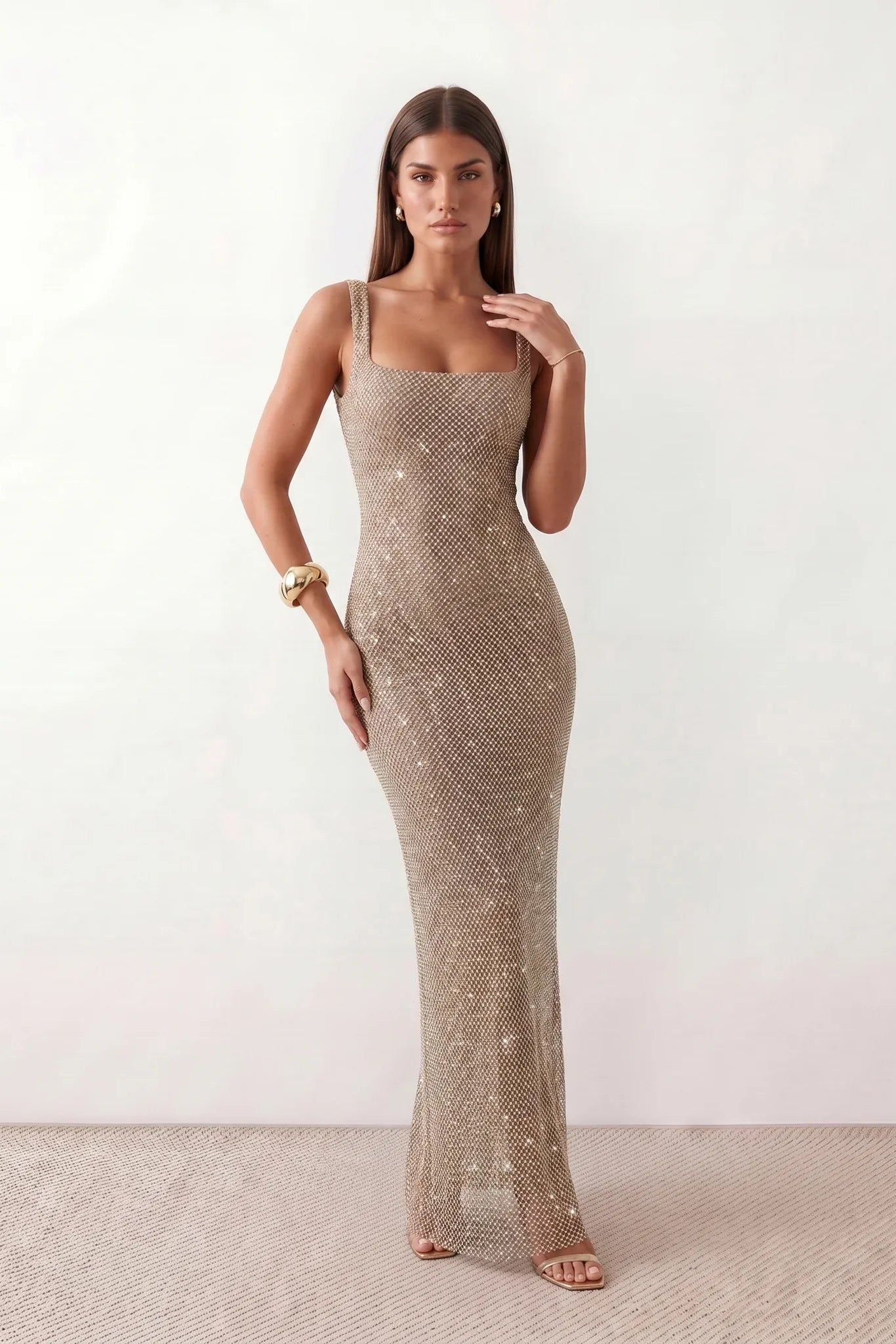 Woman wearing the Mihaela sequined low back maxi dress featuring allover sequin mesh, a square neckline, wide shoulder straps, a low open back, and a fitted floor-length sheath silhouette.