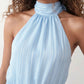 Bella Glossy Halter Mini Dress with a halter mock neckline, tie-back closure, smocked waist, open back, and tiered ruffle mini skirt in a glossy finish, available in Beige, Red, Purple, Yellow, Pink, and Light Blue.
