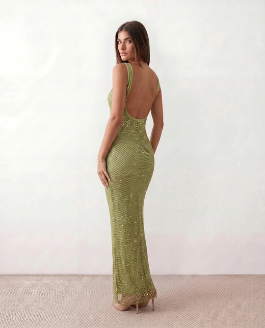 Woman wearing the Mihaela sequined low back maxi dress featuring allover sequin mesh, a square neckline, wide shoulder straps, a low open back, and a fitted floor-length sheath silhouette.
