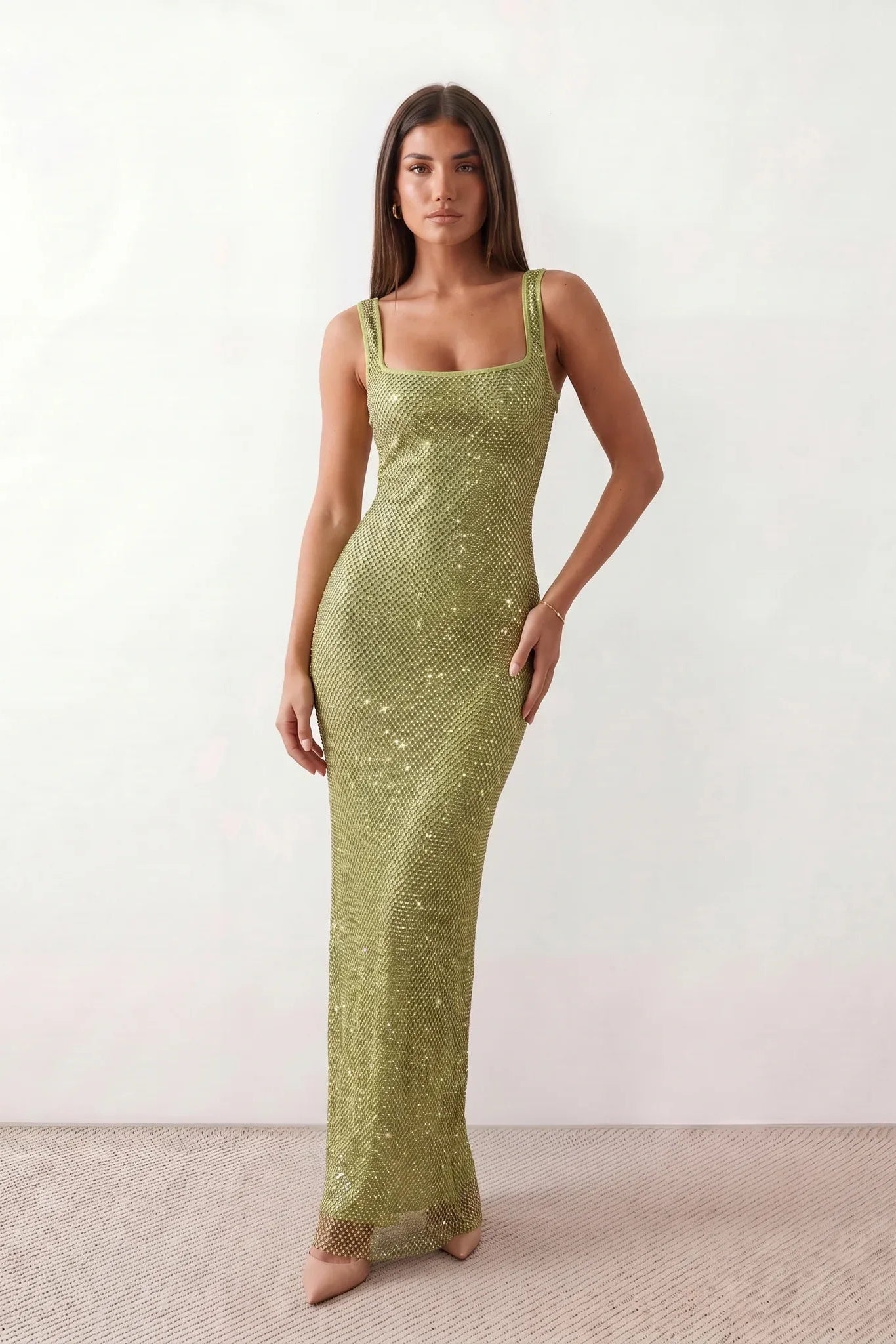 Woman wearing the Mihaela sequined low back maxi dress featuring allover sequin mesh, a square neckline, wide shoulder straps, a low open back, and a fitted floor-length sheath silhouette.
