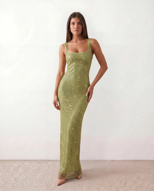Woman wearing the Mihaela sequined low back maxi dress featuring allover sequin mesh, a square neckline, wide shoulder straps, a low open back, and a fitted floor-length sheath silhouette.