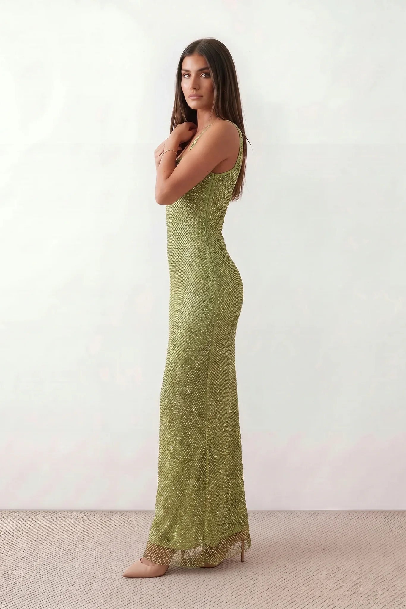 Woman wearing the Mihaela sequined low back maxi dress featuring allover sequin mesh, a square neckline, wide shoulder straps, a low open back, and a fitted floor-length sheath silhouette.