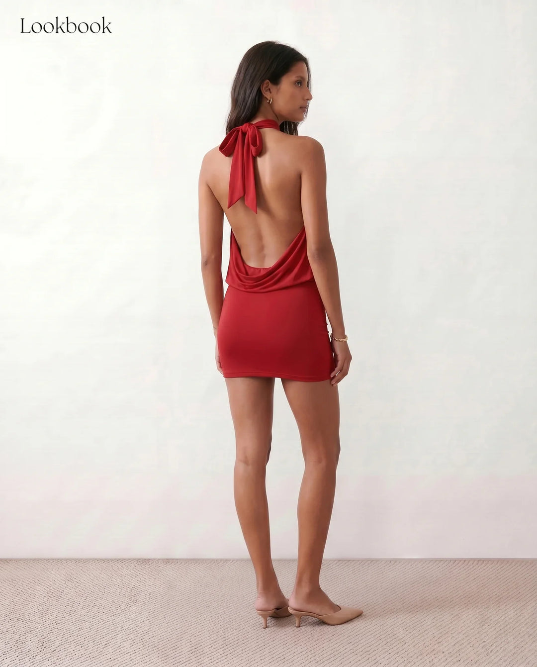 Woman wearing the Mae silk halter mini dress featuring a draped halter neckline, open back with adjustable tie-neck fastening, fitted bodycon mini silhouette, and smooth silk-look fabric, ideal for weddings, cocktail parties, and evening occasions.