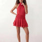 Bella Glossy Halter Mini Dress with a halter mock neckline, tie-back closure, smocked waist, open back, and tiered ruffle mini skirt in a glossy finish, available in Beige, Red, Purple, Yellow, Pink, and Light Blue.