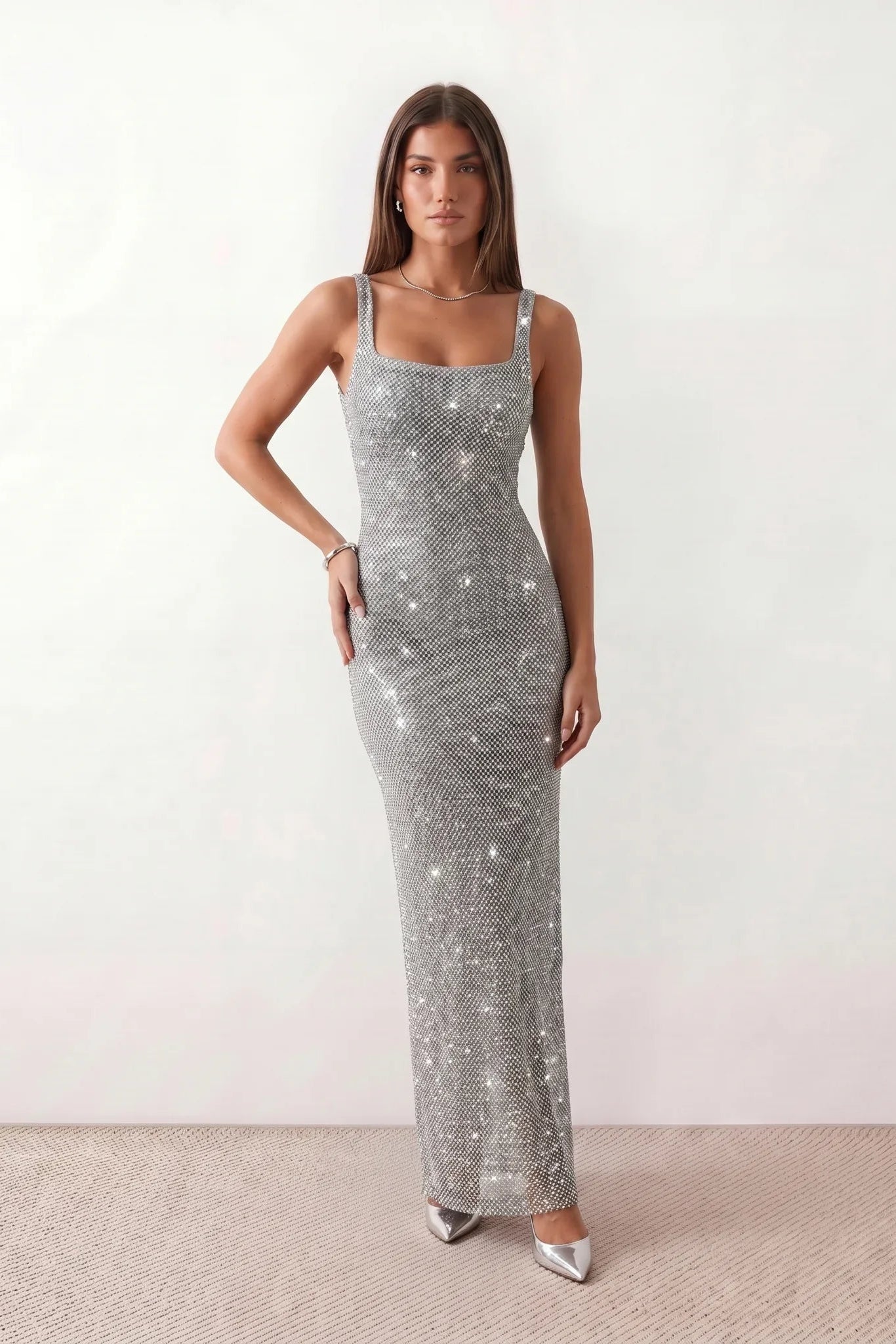Woman wearing the Mihaela sequined low back maxi dress featuring allover sequin mesh, a square neckline, wide shoulder straps, a low open back, and a fitted floor-length sheath silhouette.