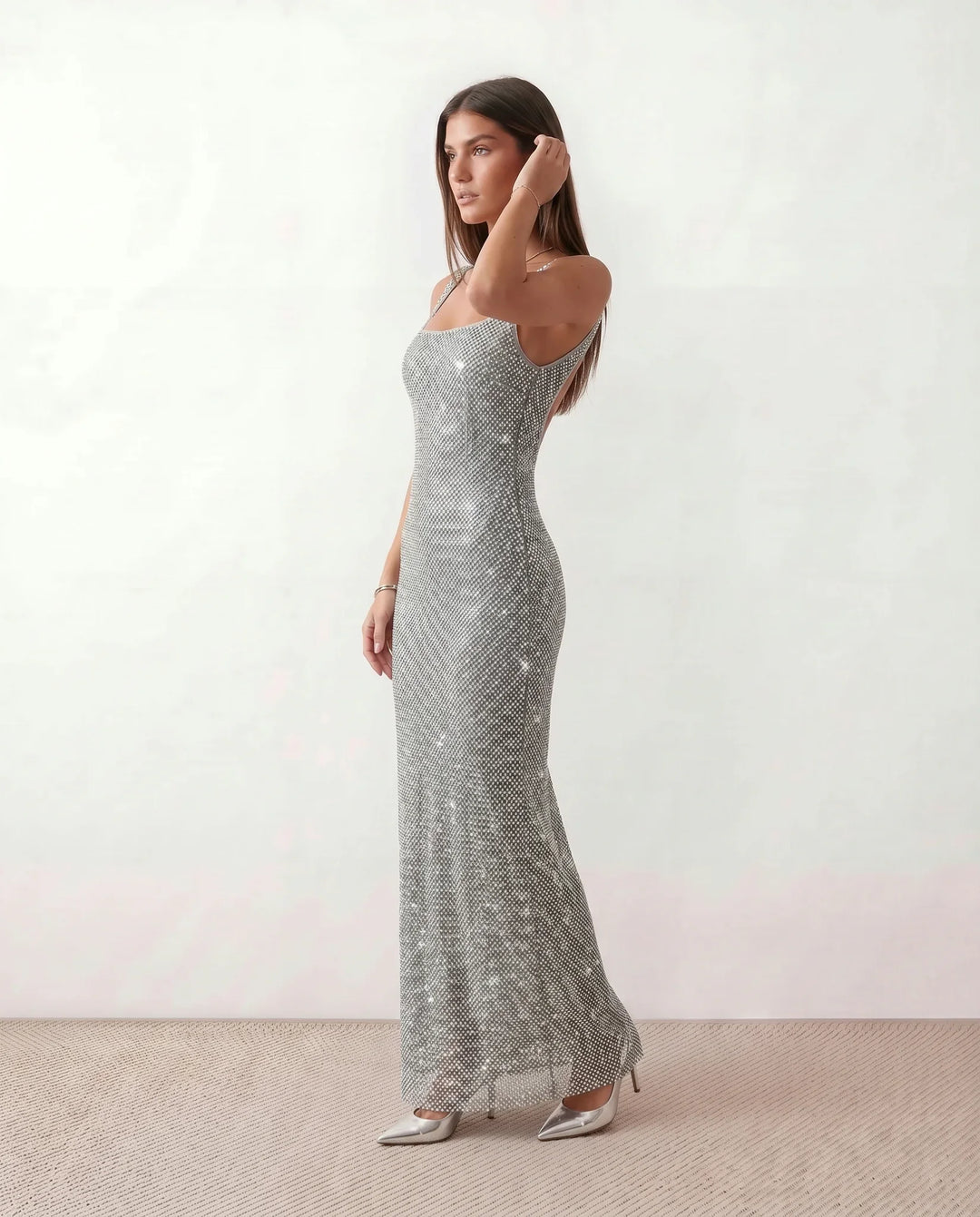 Woman wearing the Mihaela sequined low back maxi dress featuring allover sequin mesh, a square neckline, wide shoulder straps, a low open back, and a fitted floor-length sheath silhouette.