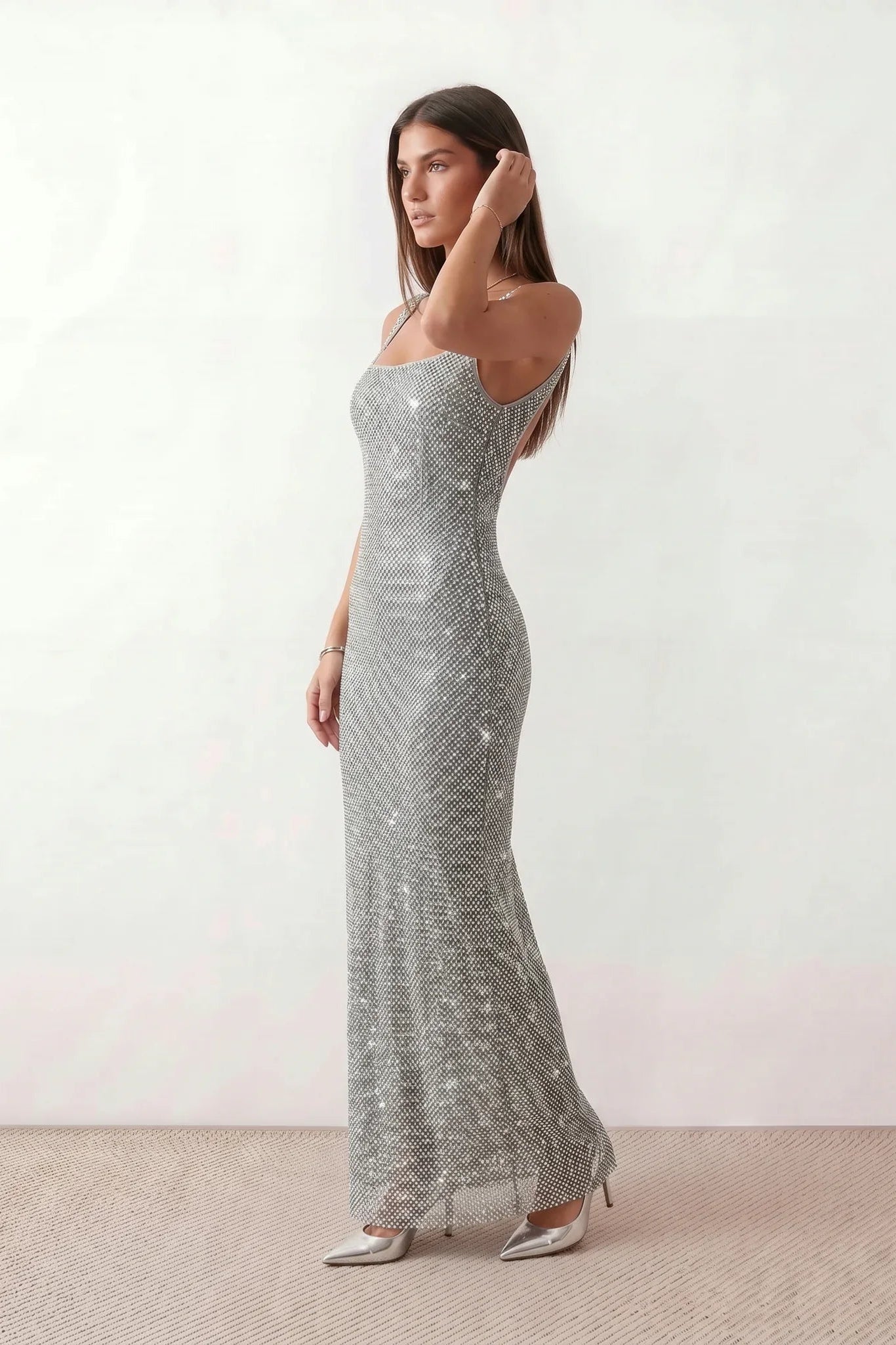 Woman wearing the Mihaela sequined low back maxi dress featuring allover sequin mesh, a square neckline, wide shoulder straps, a low open back, and a fitted floor-length sheath silhouette.