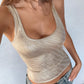 Person wearing a sparkly beige tank top and denim shorts against a light background