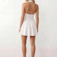 Maren halter backless mini dress with a square halter neckline, corset-seamed bodice, fully open back with tie-neck closure, and a flared A-line mini skirt. Available in black and white.