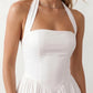 Maren halter backless mini dress with a square halter neckline, corset-seamed bodice, fully open back with tie-neck closure, and a flared A-line mini skirt. Available in black and white.