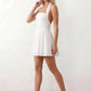 Maren halter backless mini dress with a square halter neckline, corset-seamed bodice, fully open back with tie-neck closure, and a flared A-line mini skirt. Available in black and white.