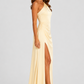 Woman wearing a soft beige asymmetric maxi dress with a one-shoulder neckline, fitted bodice, elegant draped silhouette and thigh-high side split, styled for weddings, evening events and formal occasions.