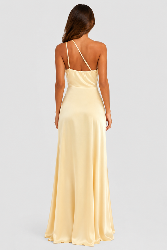 Woman wearing a soft beige asymmetric maxi dress with a one-shoulder neckline, fitted bodice, elegant draped silhouette and thigh-high side split, styled for weddings, evening events and formal occasions.