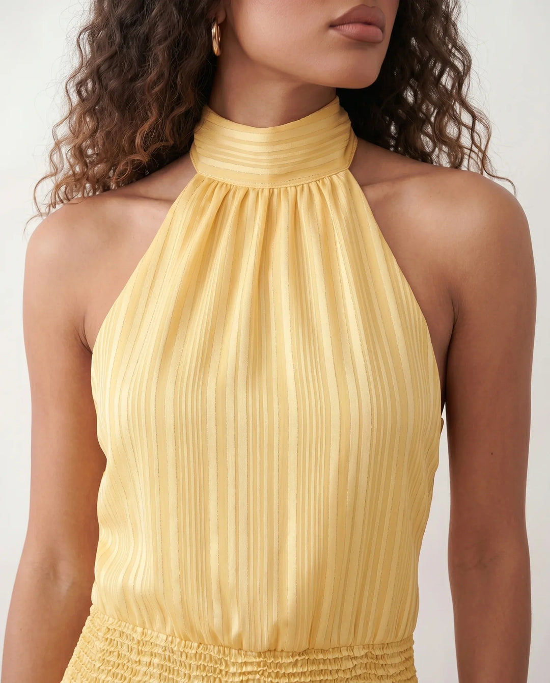 Bella Glossy Halter Mini Dress with a halter mock neckline, tie-back closure, smocked waist, open back, and tiered ruffle mini skirt in a glossy finish, available in Beige, Red, Purple, Yellow, Pink, and Light Blue.